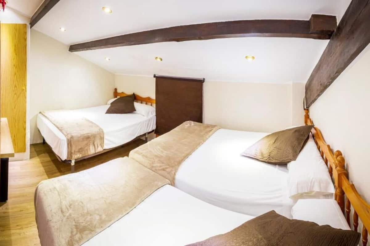 Ein Zimmer mit zwei Einzelbetten, Holz-Kopfteilen und einem Holzbalken an der Decke.