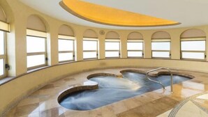 A spa with a central hot tub, arched windows, and a curved ceiling.