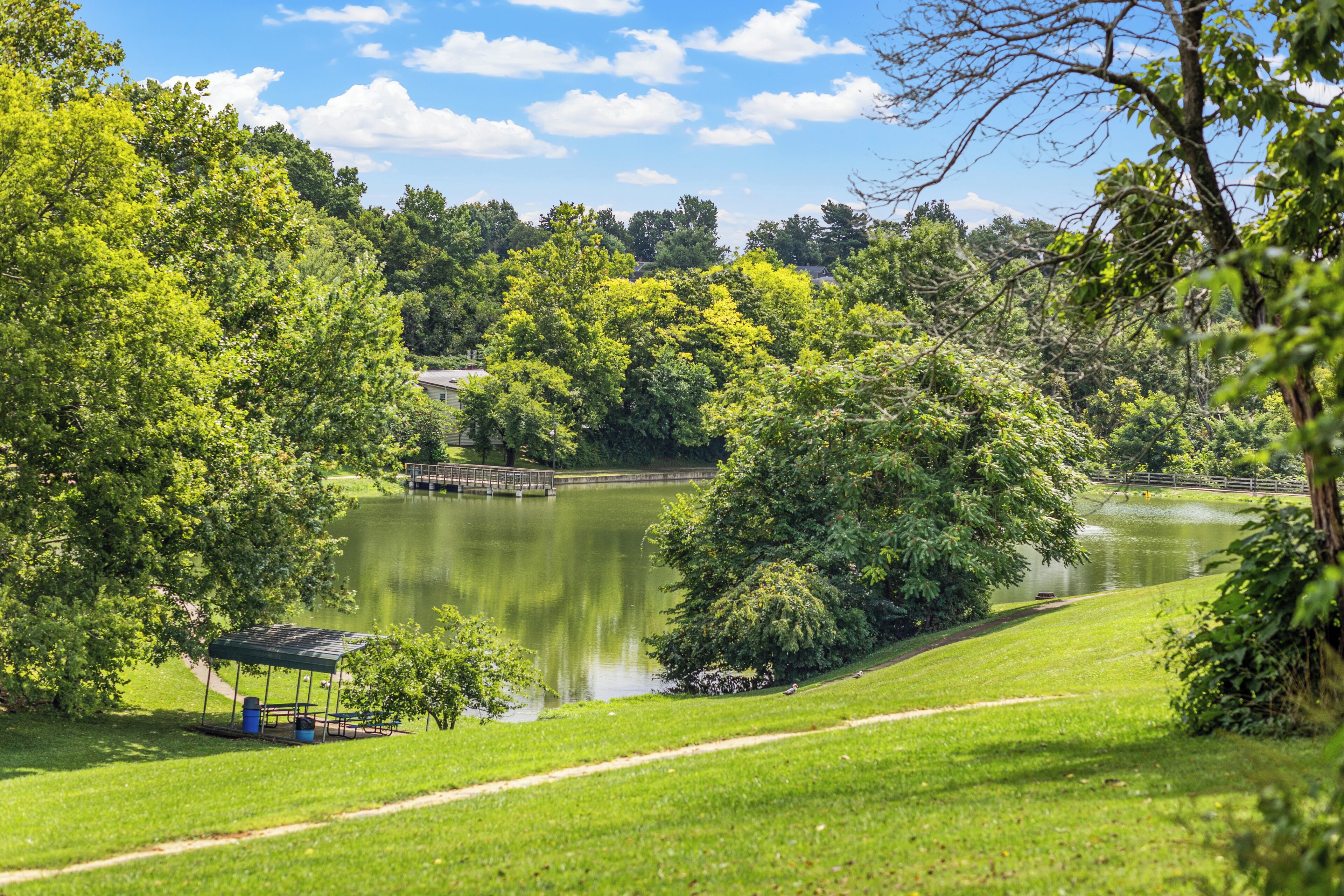 Un parque con un lago, un quiosco y un puente.
