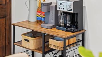 Une machine à café, un pichet et une bouteille de sirop Torani sur une table en bois.