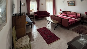 Un ampio soggiorno con un divano, una poltrona, un tavolino e una televisione.