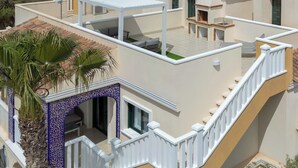 Una terraza en la azotea con pérgola, mobiliario exterior y vistas del paisaje circundante.