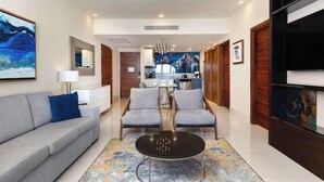 Una sala de estar moderna con un sofá, dos sillones, una mesa de centro y un televisor.