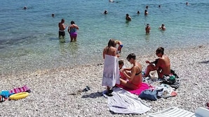 A pebbled beach with people swimming and sunbathing. - A1 Apartment With Terrace, 1 min Walk to the Beach (Supetar)