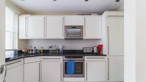 Eine moderne Küche mit weißen Schränken, einem Einbauofen, einer Mikrowelle und einem Toaster.
