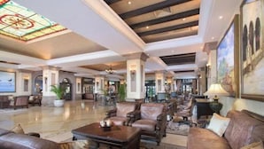 A spacious lobby with leather sofas, a coffee table, and a stained glass ceiling.