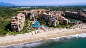 A resort with multiple high-rise buildings, a central pool, and a beach area.