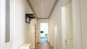 A hallway with a coat rack, a radiator, and a door leading to a room.