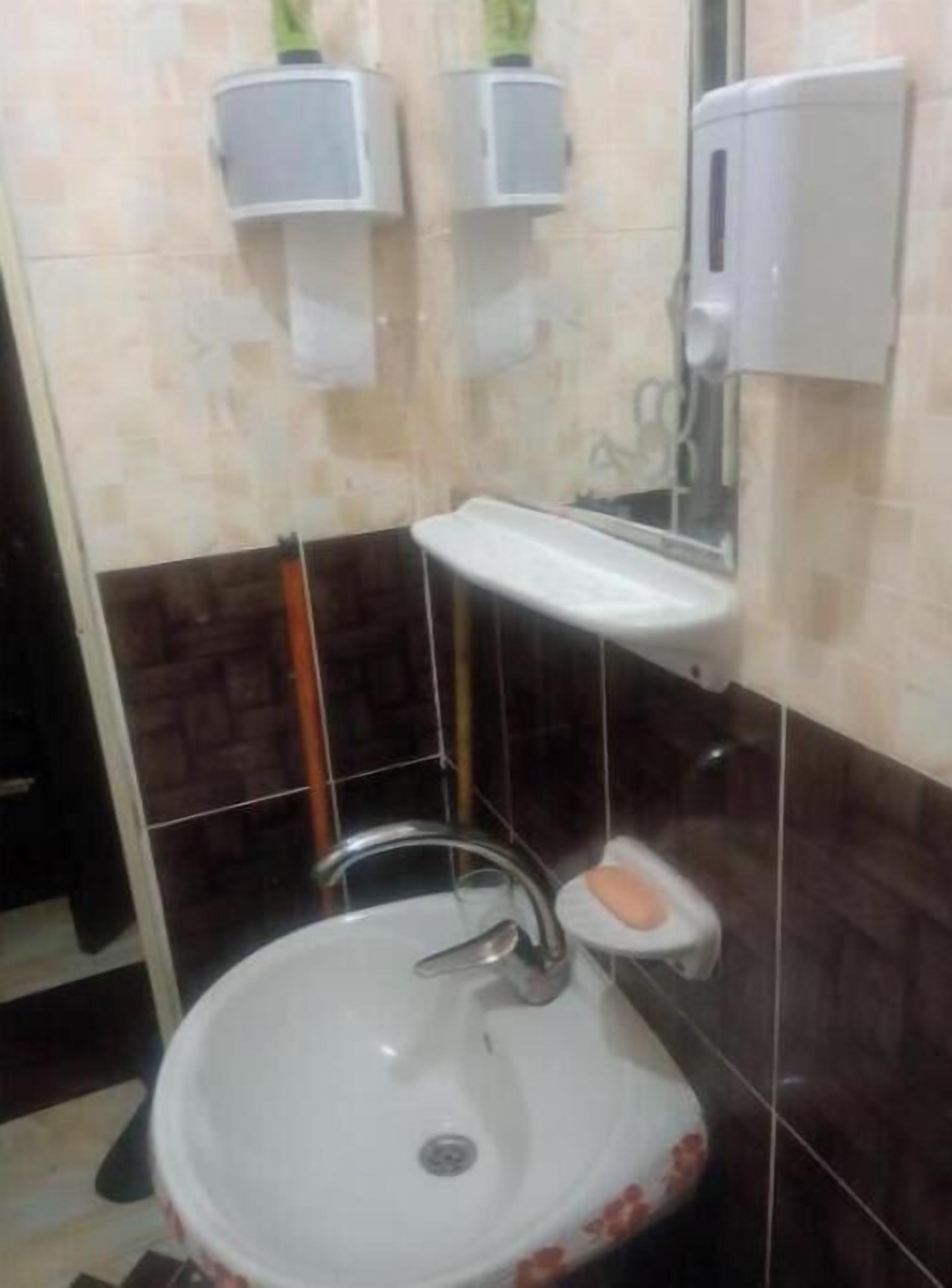 A bathroom with a white sink, a mirror, and two soap dispensers mounted on the wall.