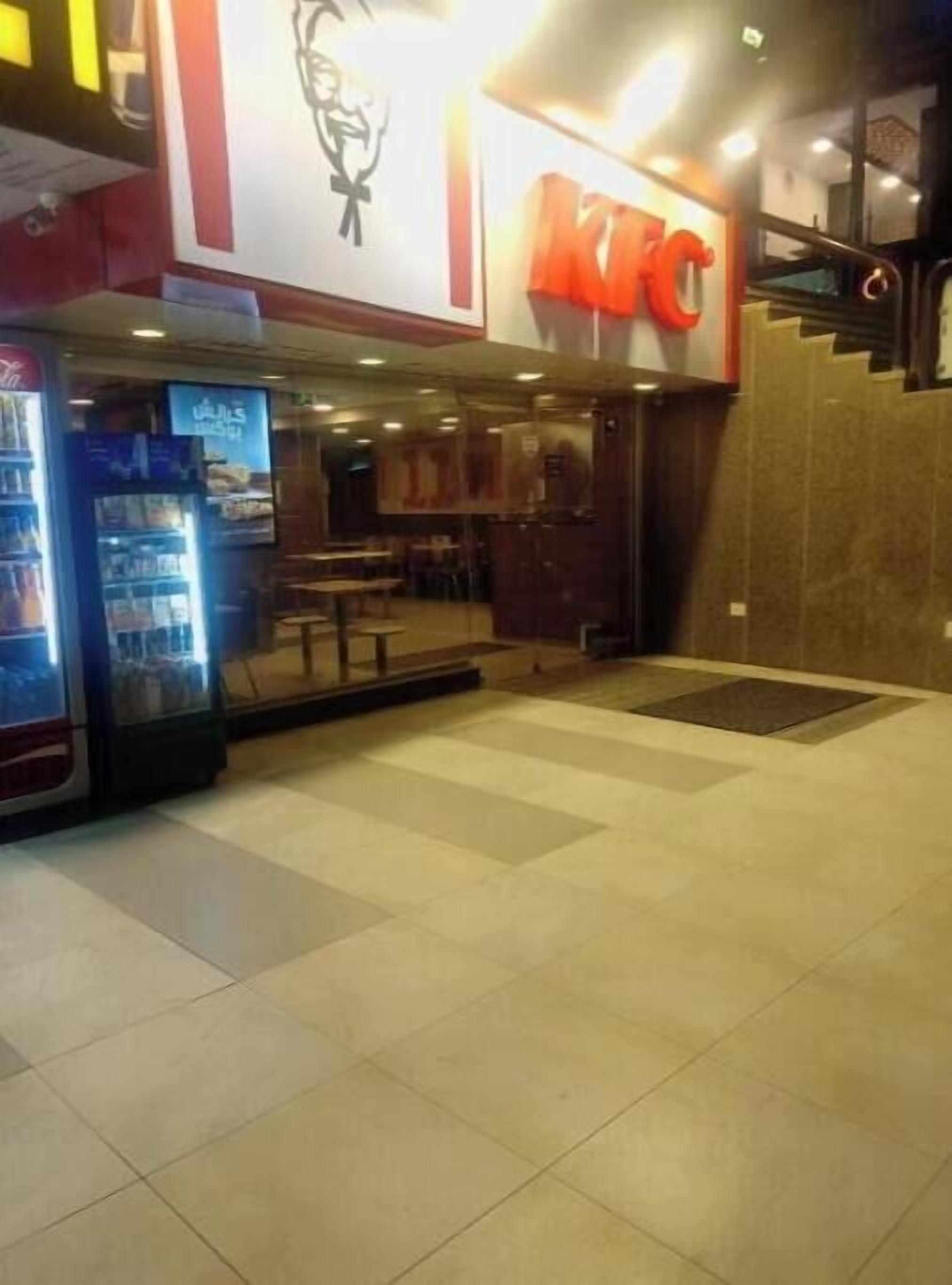 Un restaurant KFC avec un sol carrelé et un distributeur automatique situé sur la gauche.