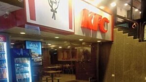 Un restaurant KFC avec un sol carrelé et un distributeur automatique situé sur la gauche.