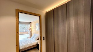A bedroom with a bed, a wooden wardrobe, and a view of the outdoors.