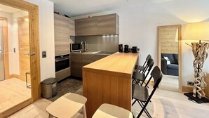 A compact kitchen with a wooden island, a dining area with chairs, and a sofa in a living space.