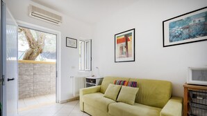 A living room with a sofa, a radiator, a window, and a door leading outside. - GuestHost - Villa Safi: Apartment A (Ostuni)