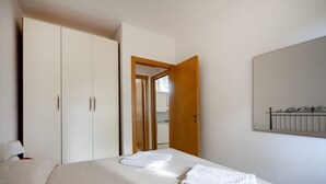 A hotel room with a bed, a wardrobe, a mirror, and a door leading to a bathroom. - GuestHost - Villa Safi: Apartment A (Ostuni)