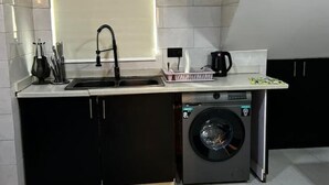 A compact kitchen with a sink, a coffee maker, and a washing machine. - 🌟 Luxurious 4-Bedroom Penthouse in Parkview, Ikoyi 🌟 (Lagos)