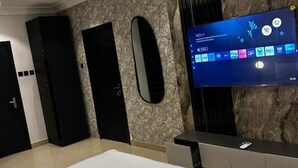 A modern hotel room with a large TV displaying a digital interface, a marble wall, and a sleek black door. - 🌟 Luxurious 4-Bedroom Penthouse in Parkview, Ikoyi 🌟 (Lagos)