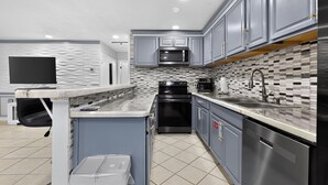 A modern kitchen with grey cabinets, a microwave, stove, and a sink. - Modern In-Law Suite Near Jax Beaches & Mayo (Jacksonville)
