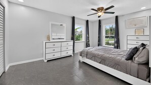 A bedroom with a bed, a dresser, a ceiling fan, and a window with curtains. - Modern In-Law Suite Near Jax Beaches & Mayo (Jacksonville)