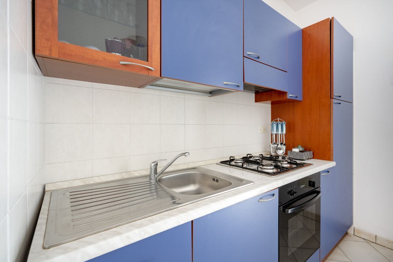 A kitchen with a stainless steel sink, a gas stove, and a built-in oven.