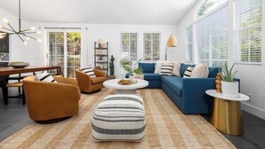 A modern living room with a sectional sofa, two armchairs, a round coffee table, and a patterned rug. - Private Hilltop Escape: Pool, Hot Tub, Near Beach (Vista)
