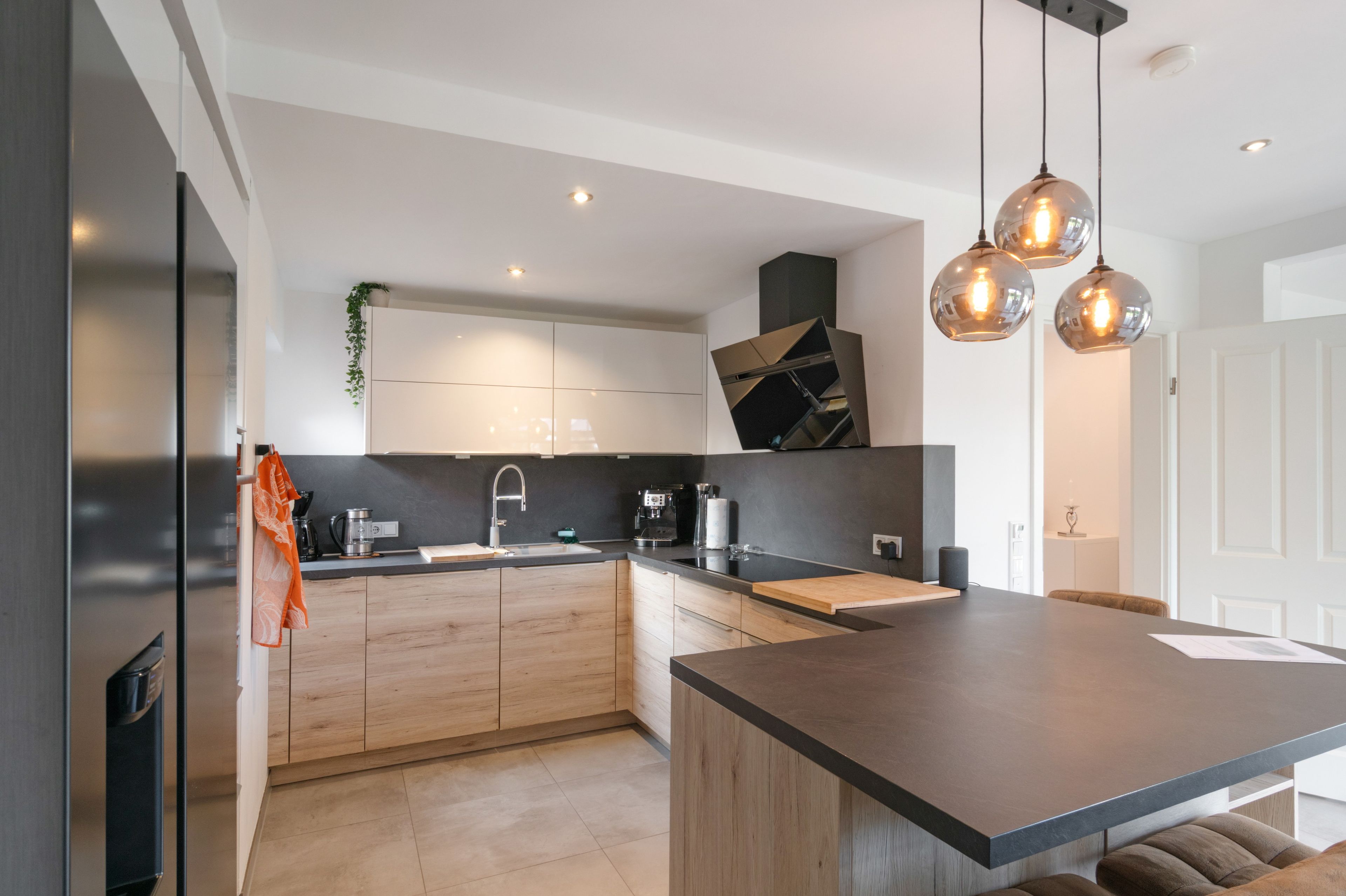 Una cocina moderna con una isla central, electrodomésticos integrados e iluminación colgante.