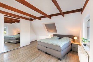 A bedroom with a bed, bedside tables, a window, and a view of the outdoors. - Holiday Home 'Neeborg' with Private Terrace, Garden, and Wi-Fi (Zetel)