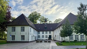En bygning med en symmetrisk facade, en midterindgang og en belagt gårdsplads.