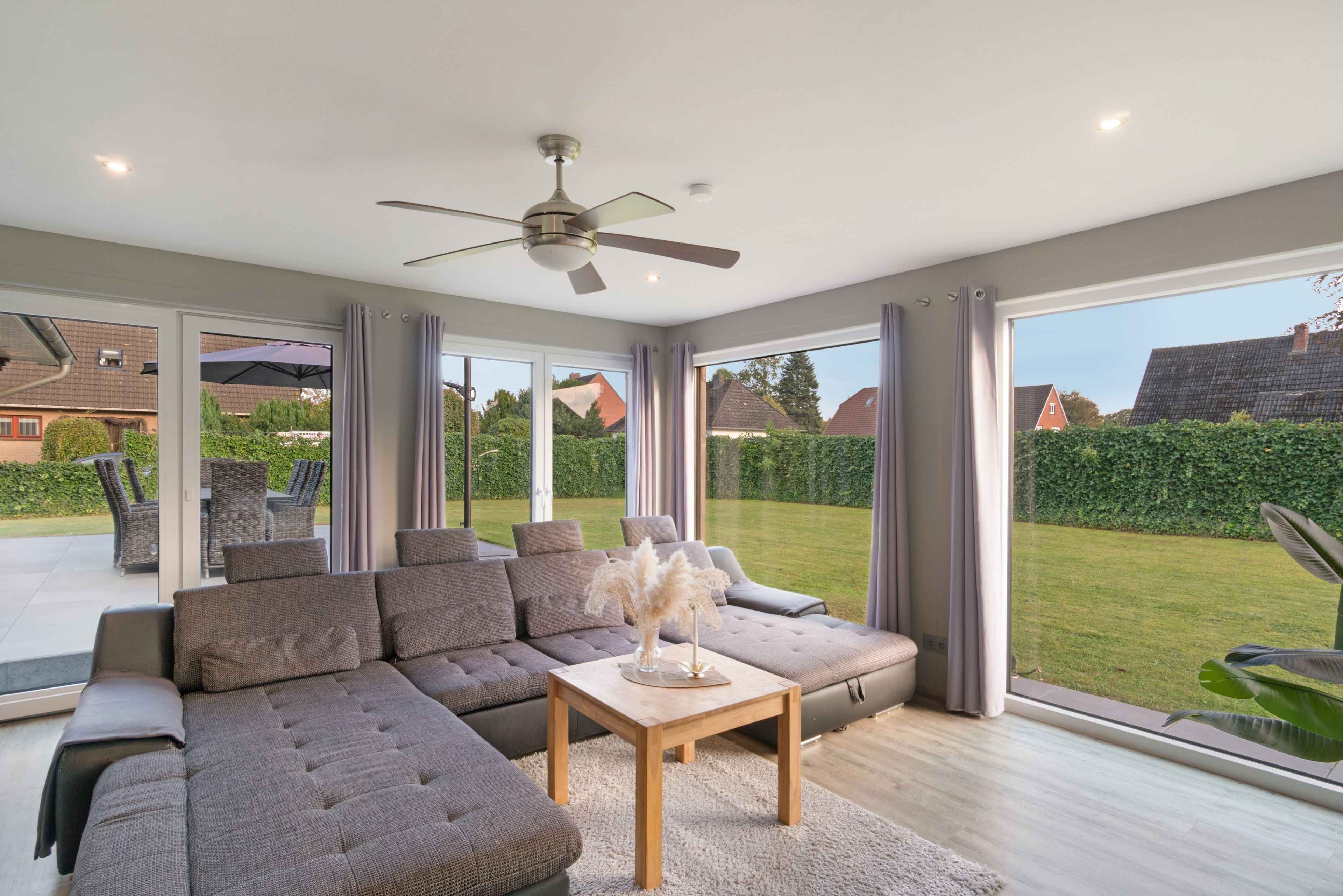 A modern living room with a sectional sofa, a wooden coffee table, and a ceiling fan.