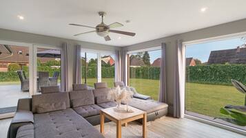 A modern living room with a sectional sofa, a wooden coffee table, and a ceiling fan.