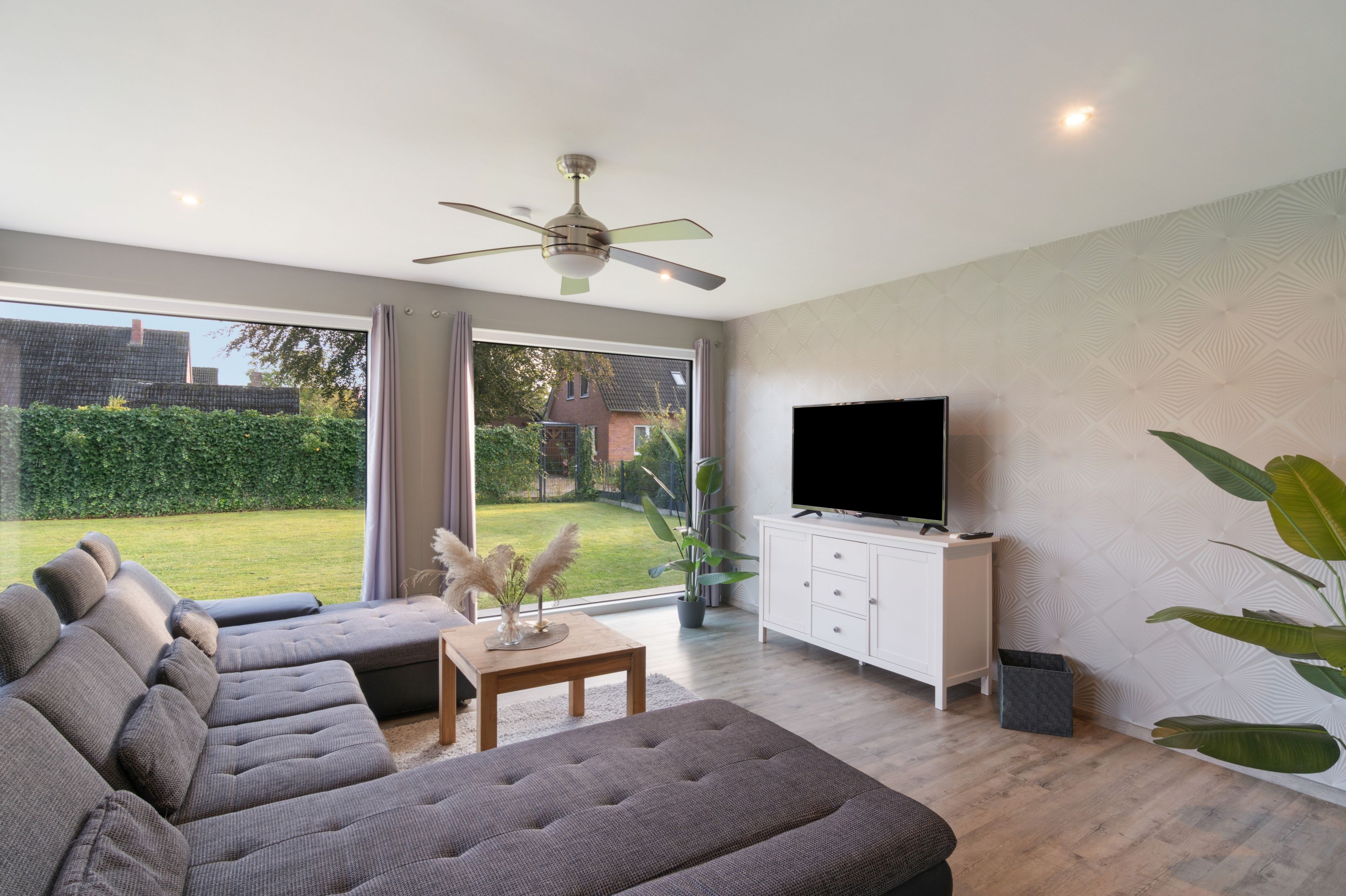 Un soggiorno moderno con un divano, una TV a schermo piatto e una ventola a soffitto.