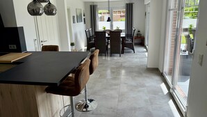 Et moderne køkken med en central ø, barstole og et spiseområde med et bord og stole.