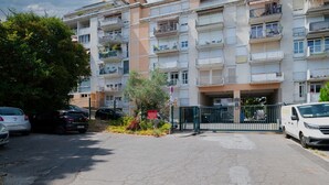Ein mehrgeschossiges Wohngebäude mit Balkonen, einem verschlossenen Eingang und geparkten Autos.