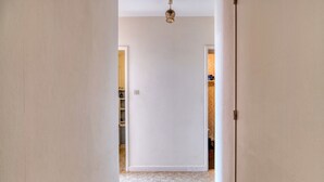 Ein Flur mit Deckenventilator, einer Tür rechts und einem Schrank mit Regalen links.