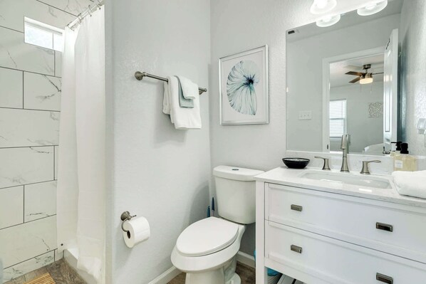 A bathroom with a white toilet, a sink with a mirror, and a shower curtain.