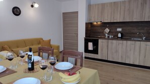 A dining area with a table set for a meal, a kitchen with wooden cabinets, and a living room with a sofa.