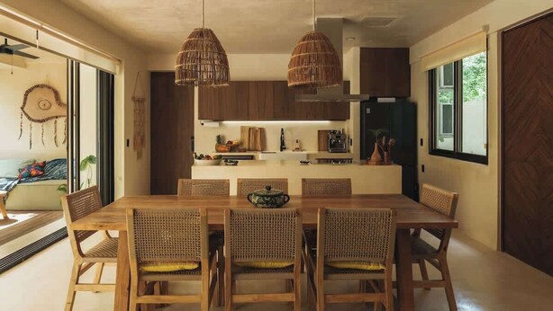 A modern kitchen with wooden cabinets, a central island, and hanging wicker pendant lights.