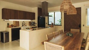 A modern kitchen with a central island, wooden cabinets, and a dining area with a large wooden table and chairs.