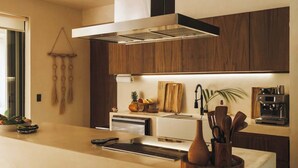 A modern kitchen with a central island, a built-in oven, and a coffee machine.