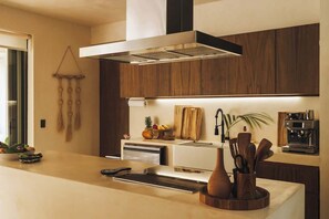 A modern kitchen with a central island, a built-in oven, and a coffee machine. - Perfect for 10 Guests w/ Rooftop & Jungle Views (Tulum)