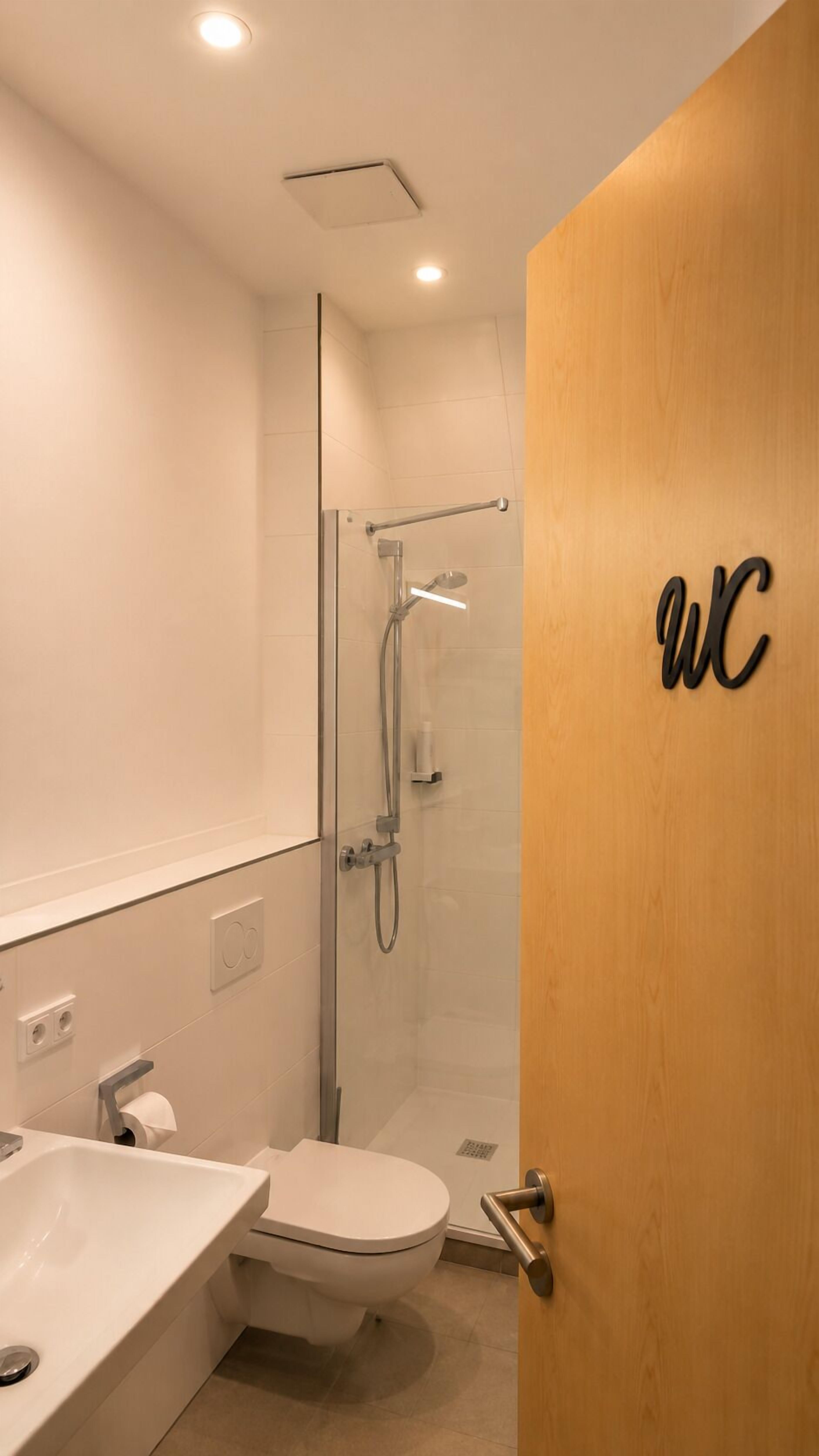 Un baño moderno con cabina de ducha de vidrio, inodoro y lavamanos.