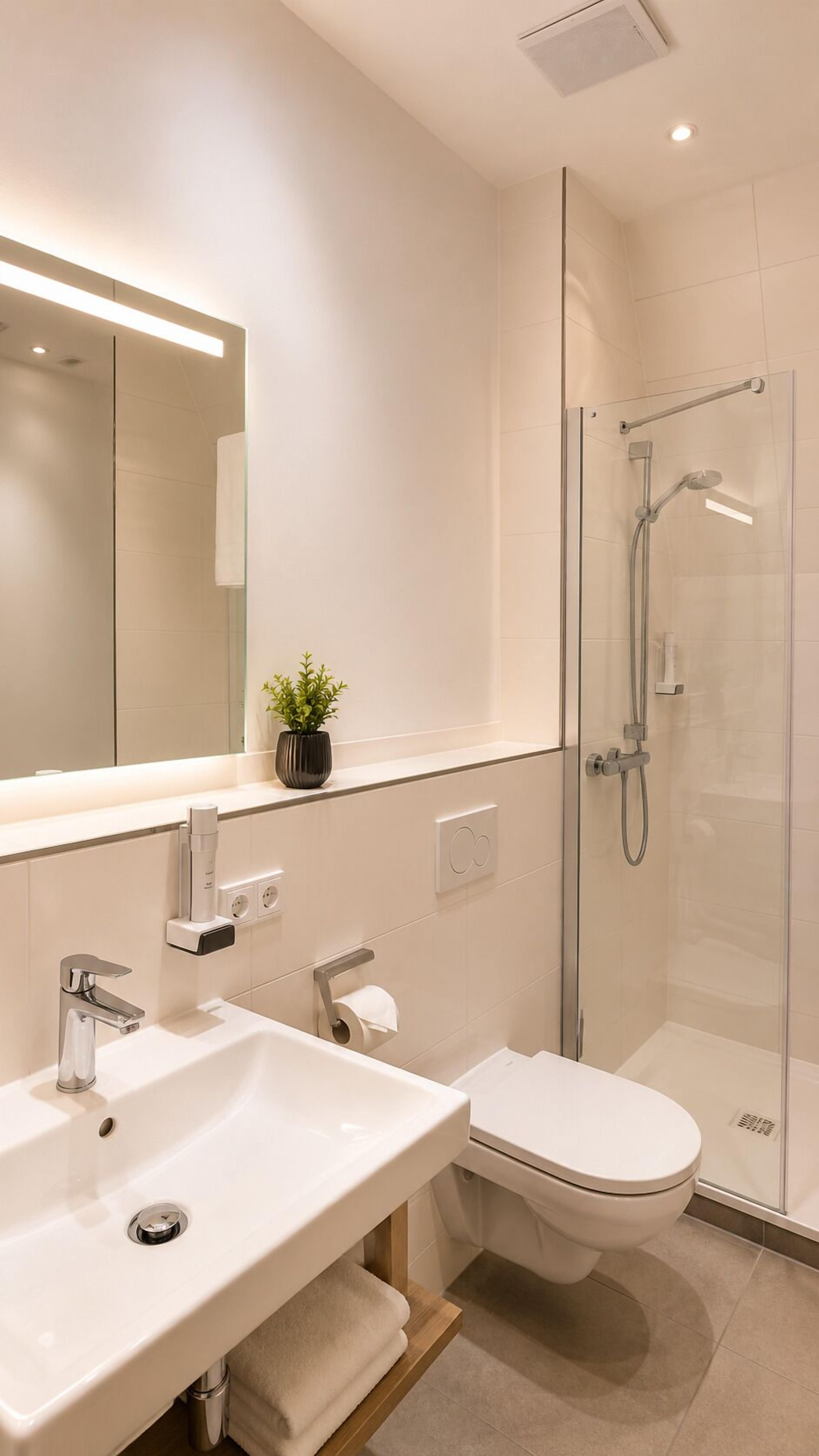 A modern bathroom with a glass shower enclosure, a white sink, and a toilet.