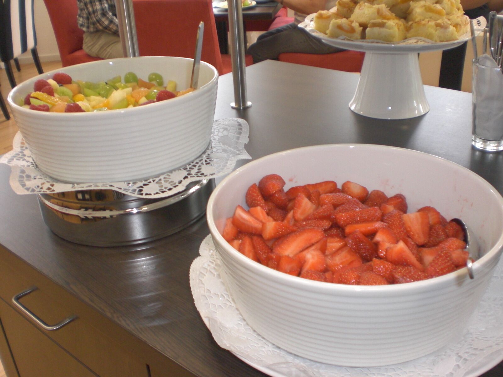 Een buffet met schalen vol fruit en een taartplateau.