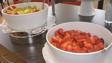 Een buffet met schalen vol fruit en een taartplateau.