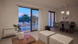 A modern living room with a large sliding glass door leading to an outdoor patio, a dining area with a table and chairs, and a small side table with a vase.