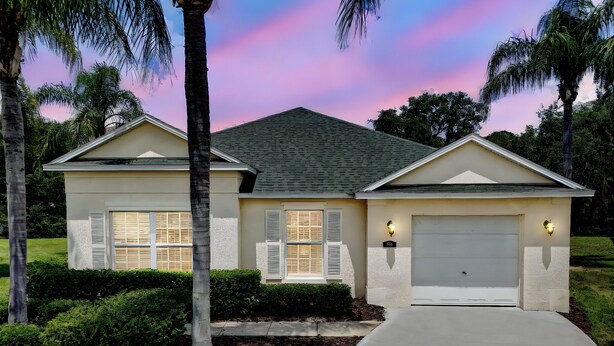 A two-story house with a garage, surrounded by palm trees and a well-maintained lawn.