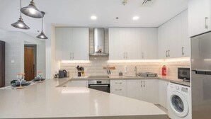 Una cocina moderna con una isla grande, electrodomésticos de acero inoxidable e iluminación colgante.