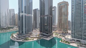 Un complejo de edificios altos con múltiples torres, una plaza central y vista al agua.