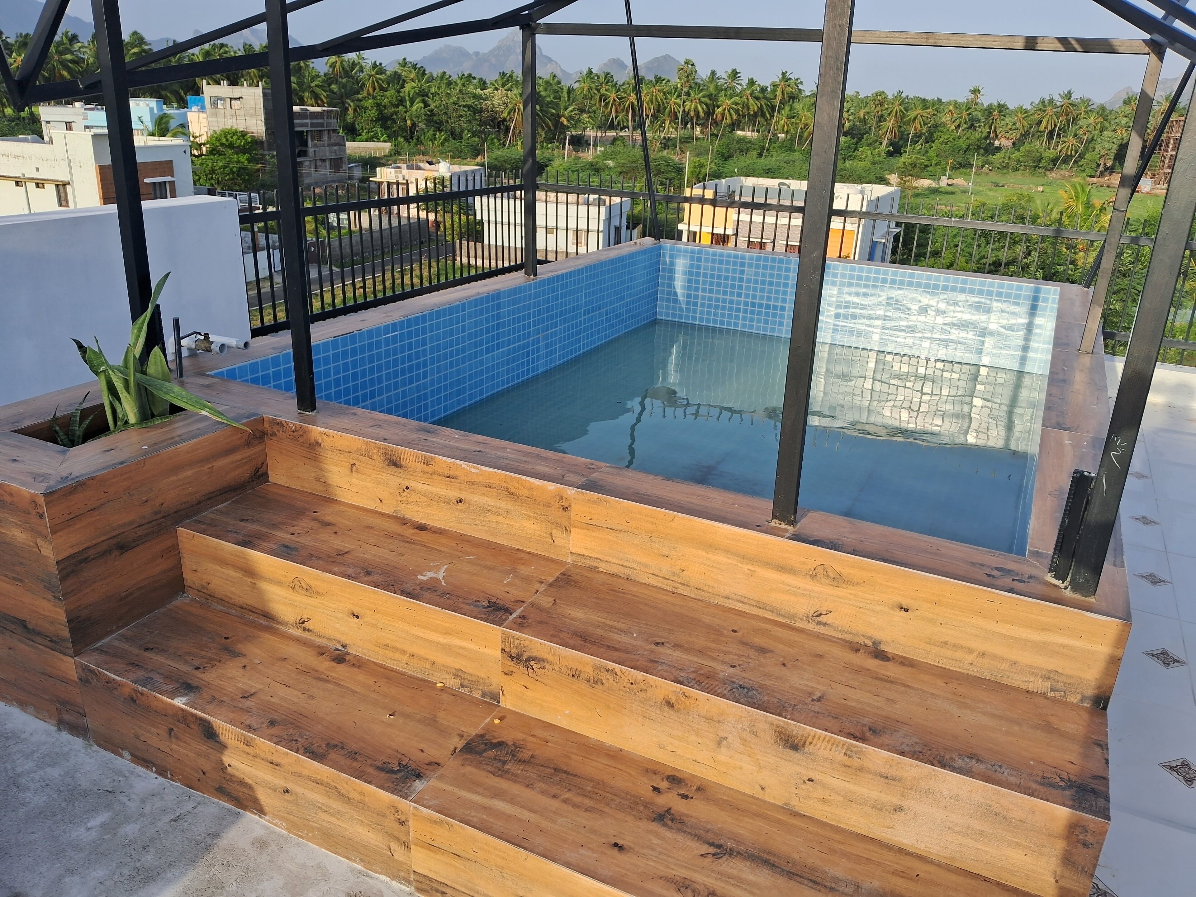 Une piscine sur le toit, avec des carreaux bleus et des marches en bois.