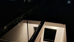 A staircase with wooden steps and white walls, leading to a small enclosed area with a window. - Luxury 2-bedroom apartment with WiFi, AC & Rooftop Jacuzzi pool near Kanyakumari (Suchindram)